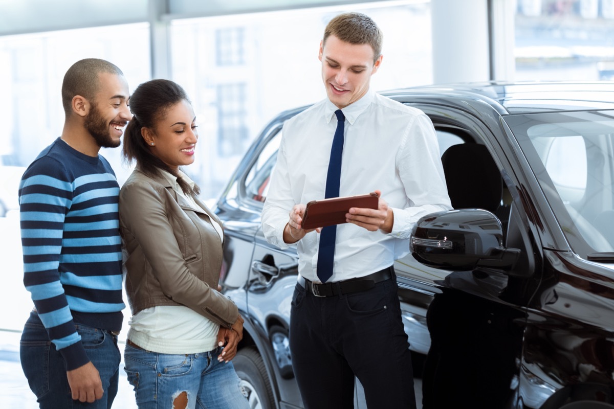 a couple talking to a car salesman at dealership