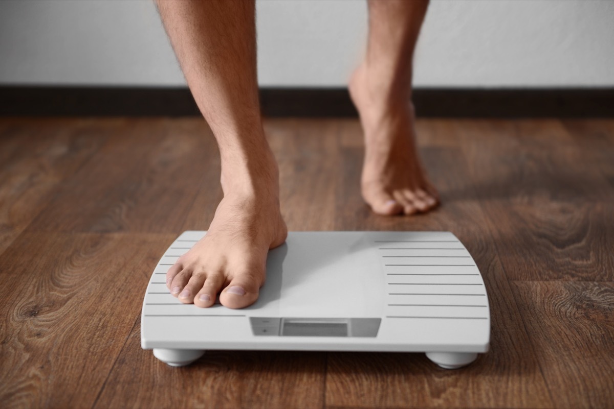 Man going on the scale looking at his weight