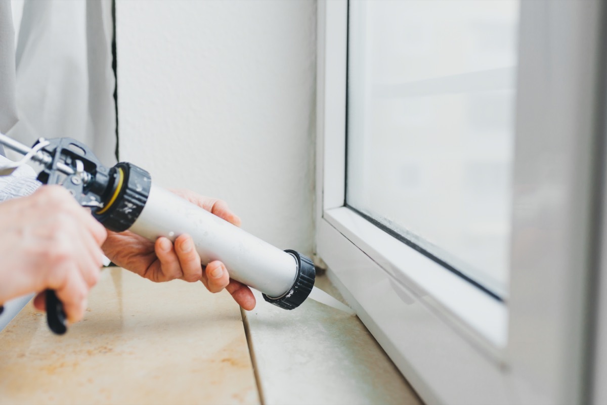 Close up of hands caulking window