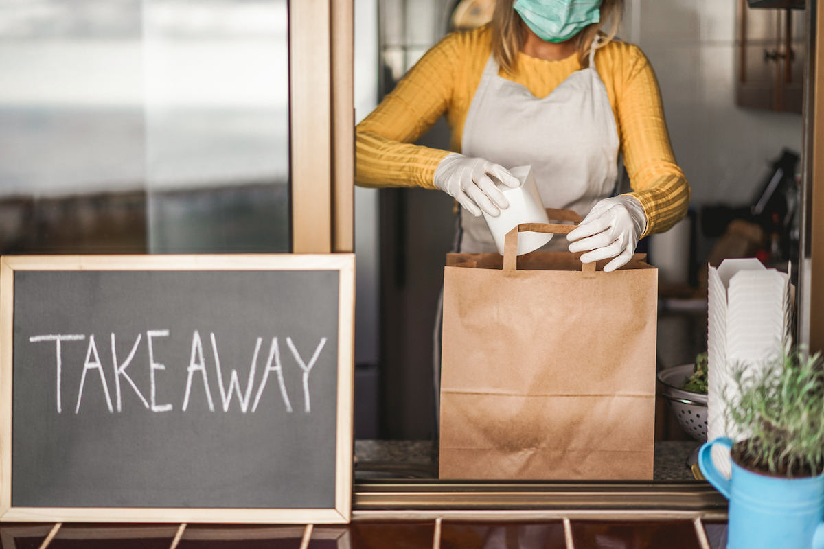 Young woman preparing takeaway food inside restaurant during Coronavirus