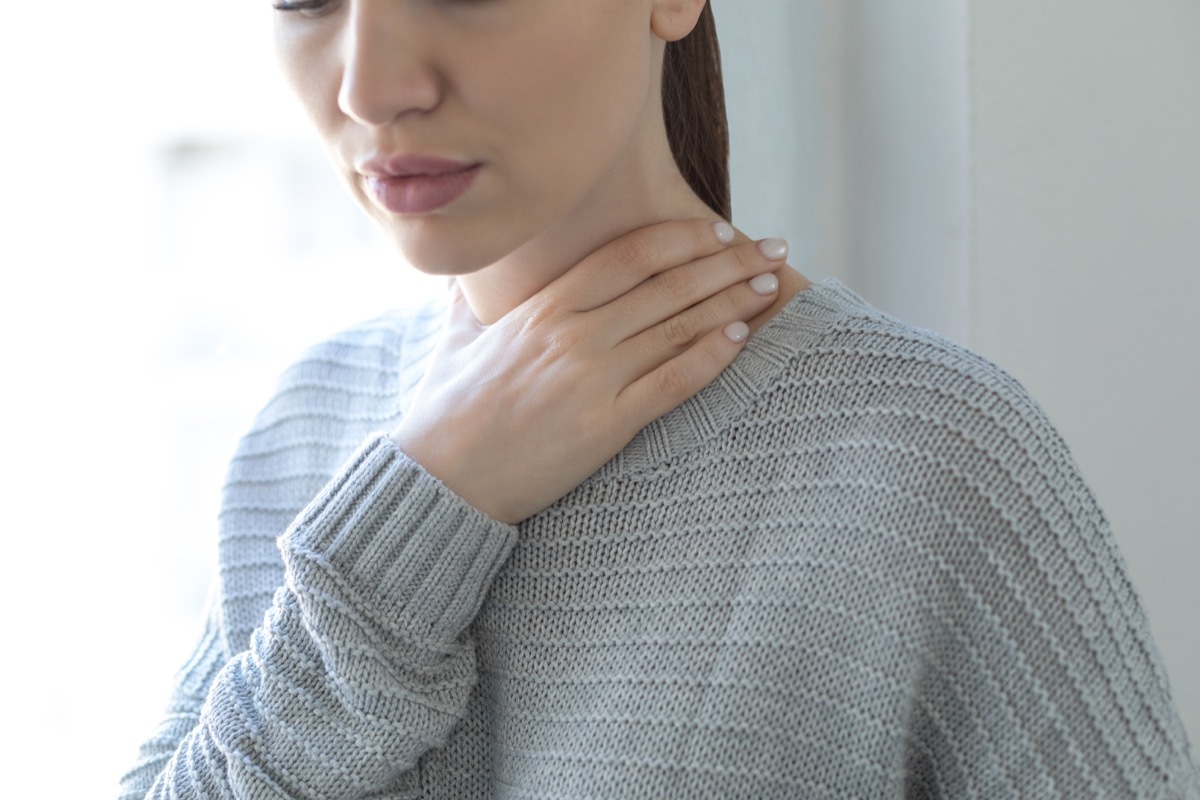 Woman touching her throat.