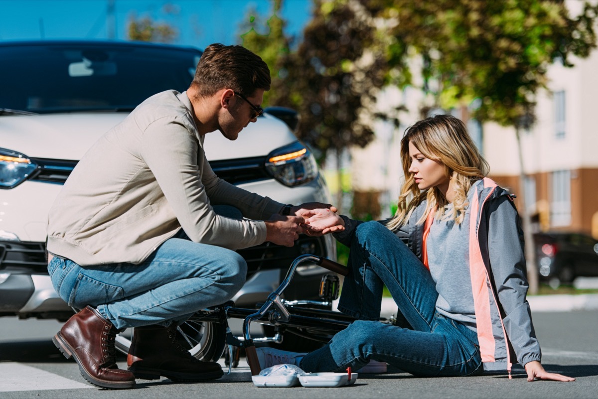 man getting first air to injured woman after car accident on road