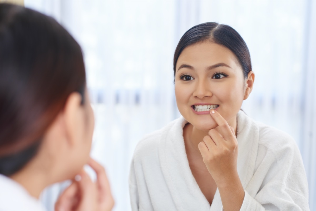 young asian woman picking food out of teeth