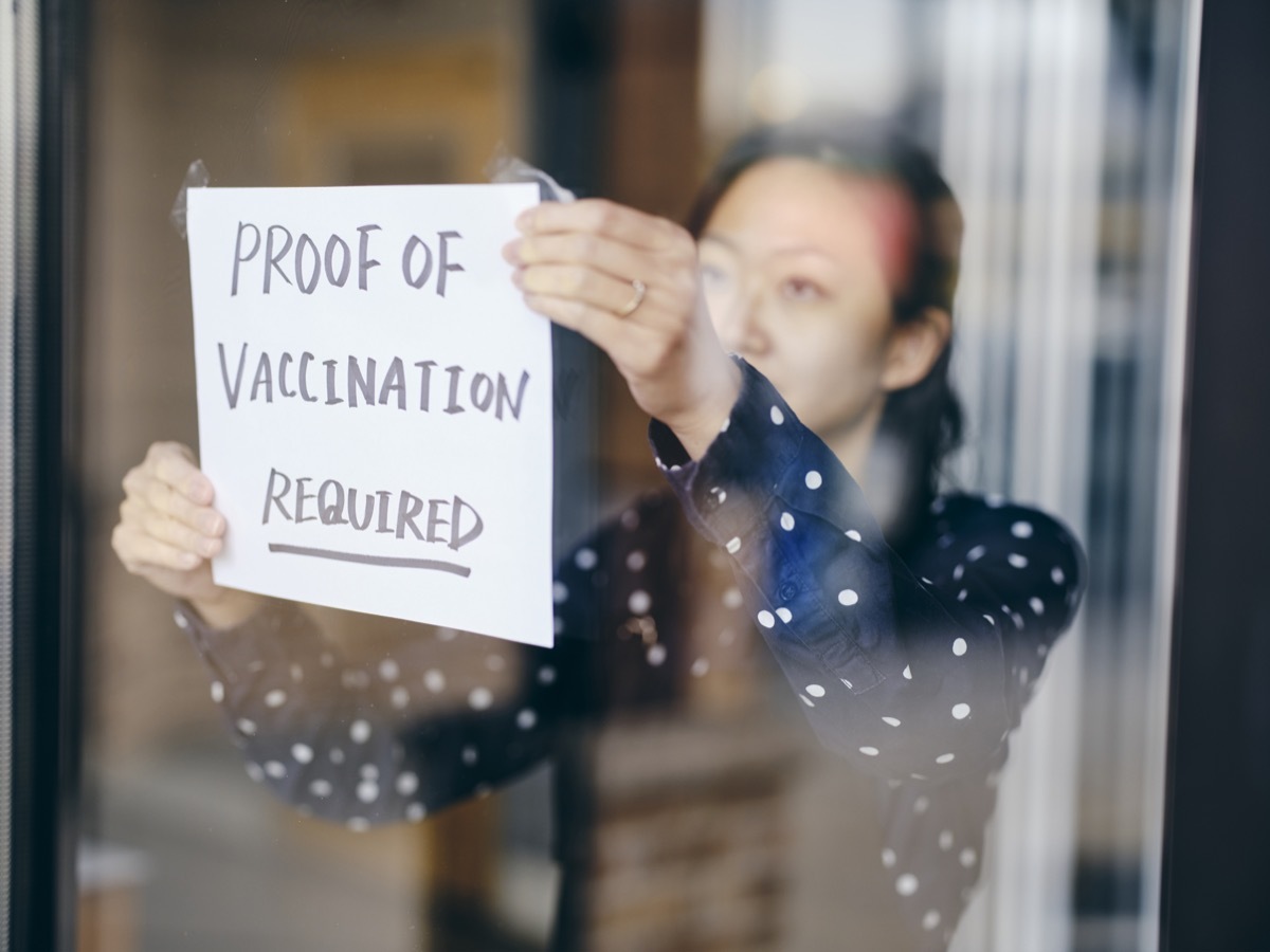 A business owner putting up a sign requiring proof of vaccination.