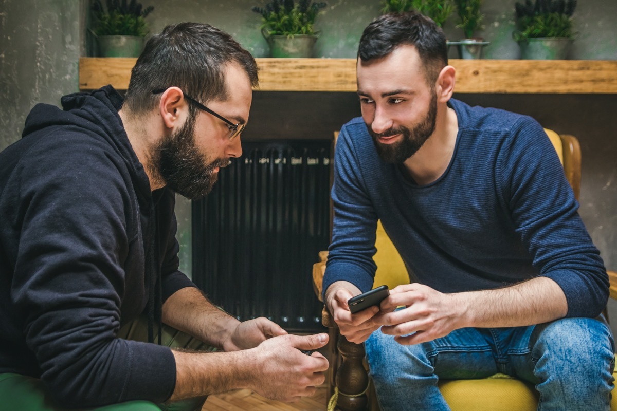 Two friends watching media content in a smart phone