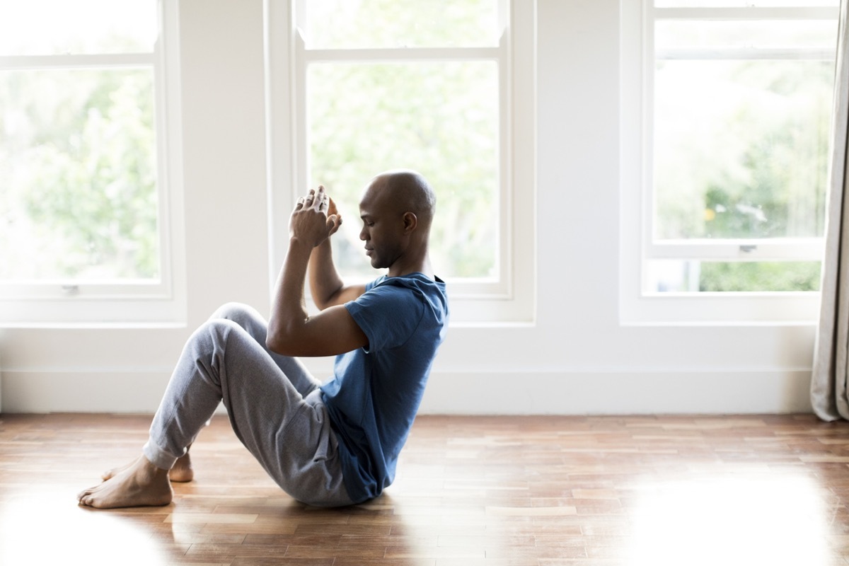 black man doing sit ups on a hardwood floor at home