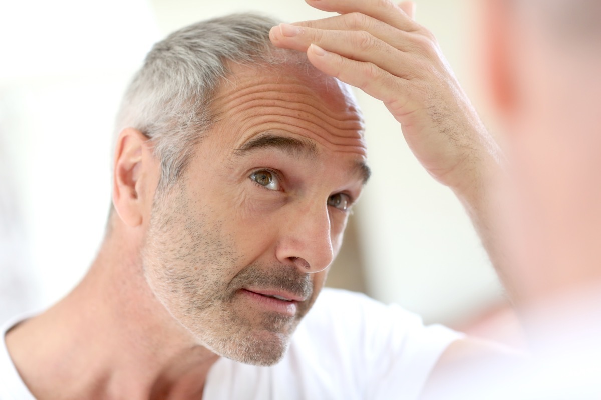 Man with gray hair looking in mirror