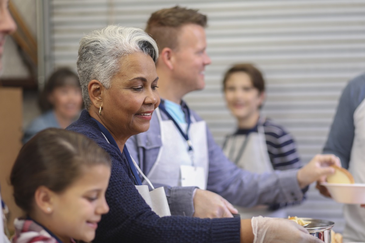 older black woman volunteering in a soup kitchen with other volunteers