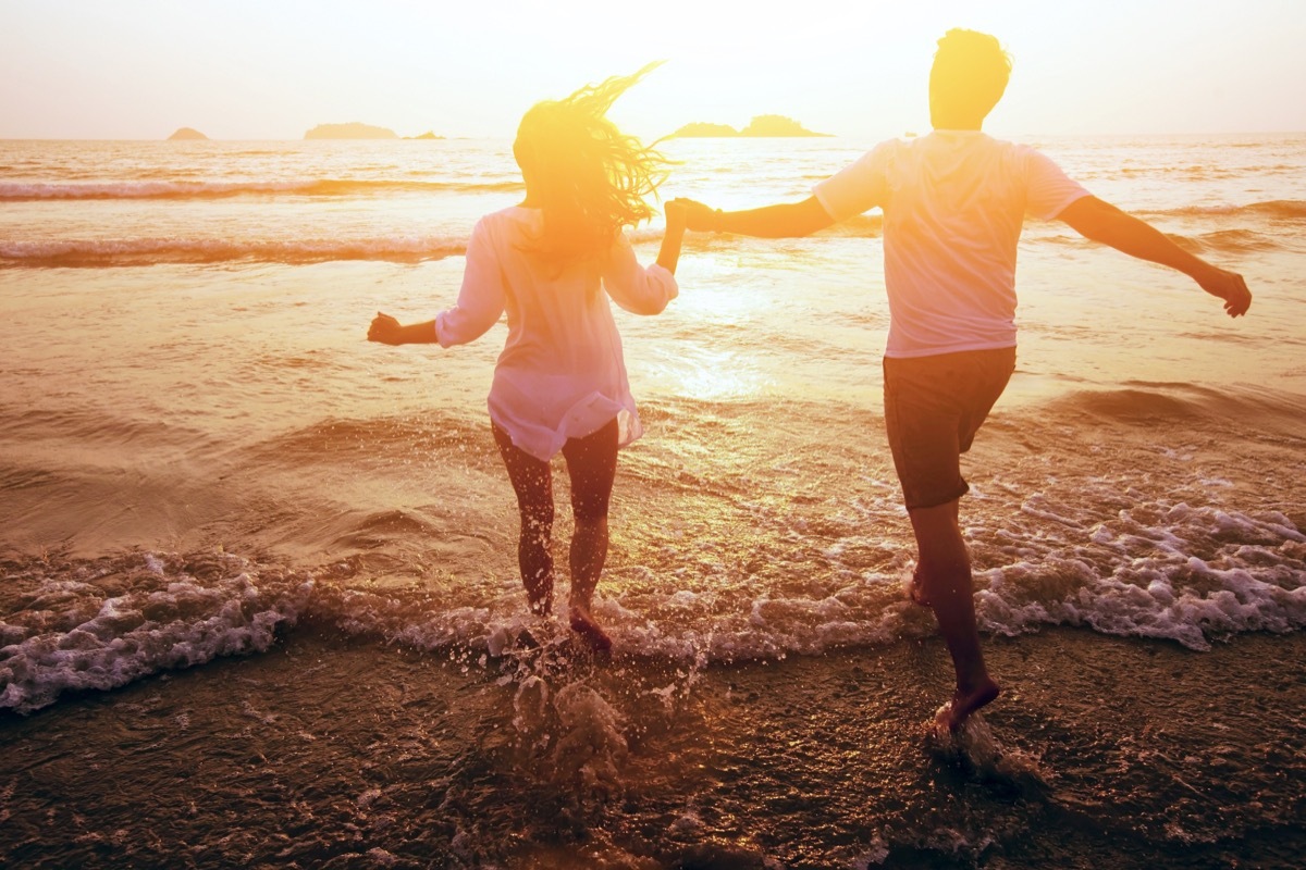 Couple running into the sunset ocean