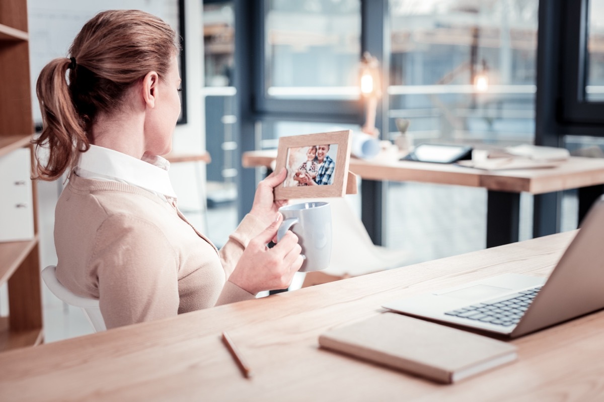 Woman looking at her family photo at her desk