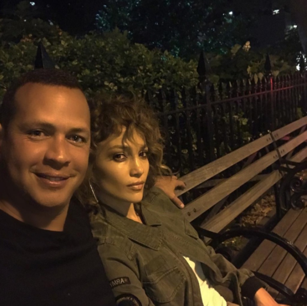 Alex Rodriguez and Jennifer Lopez on a park bench.