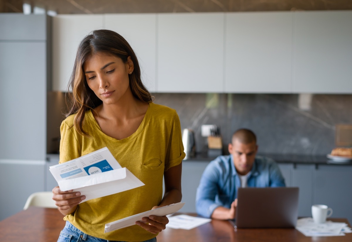 woman at home looking worried getting bills in the mail - domestic life concepts