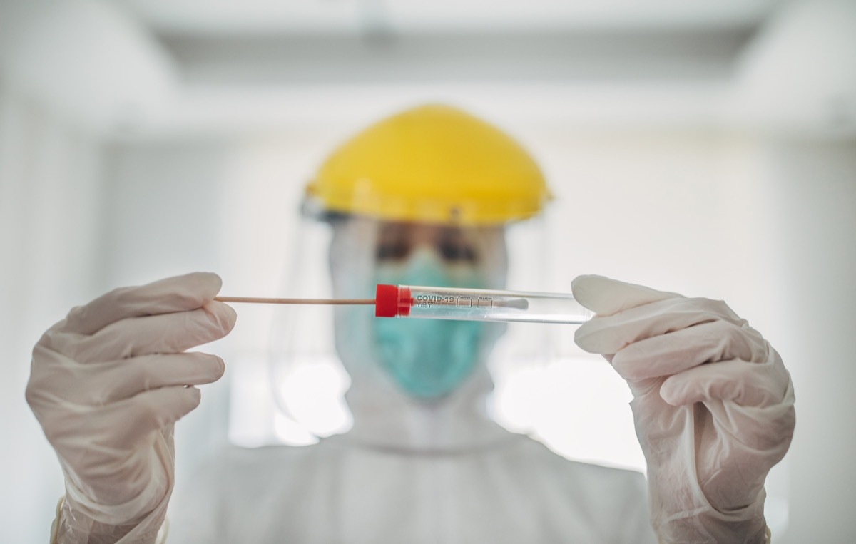 Doctor showing covid-19 tube test and sampling swab.