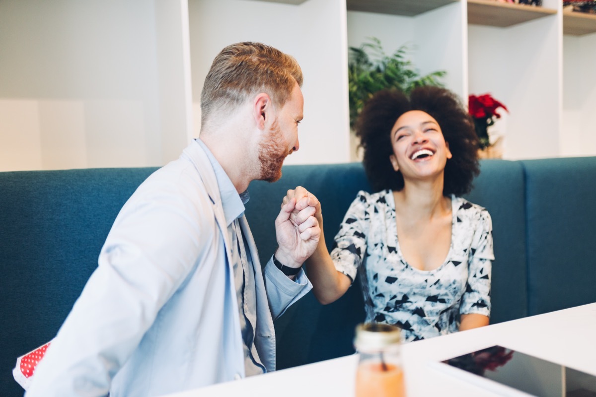 man holding his friends hand at a restaurant giving her compliments