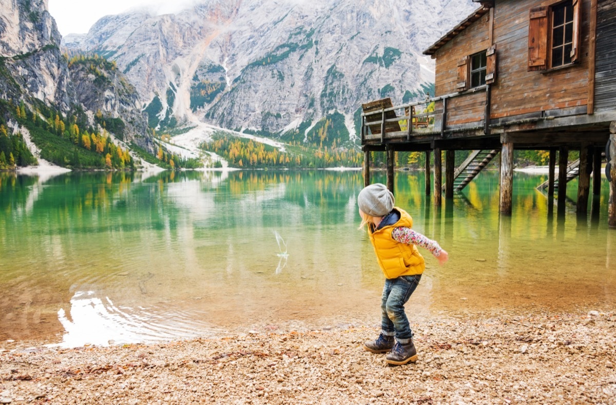 Little girl skipping stones on a beautiful lake