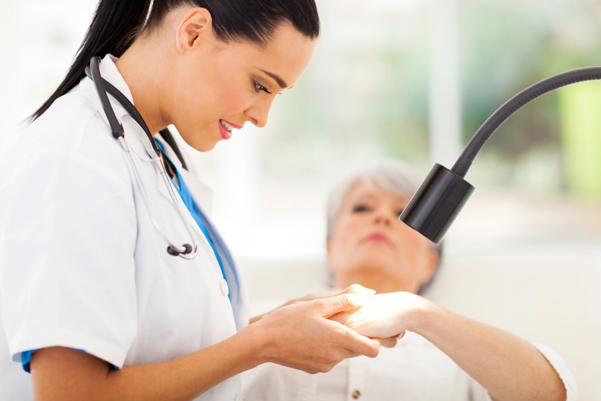 Doctor looking at woman's hands under light