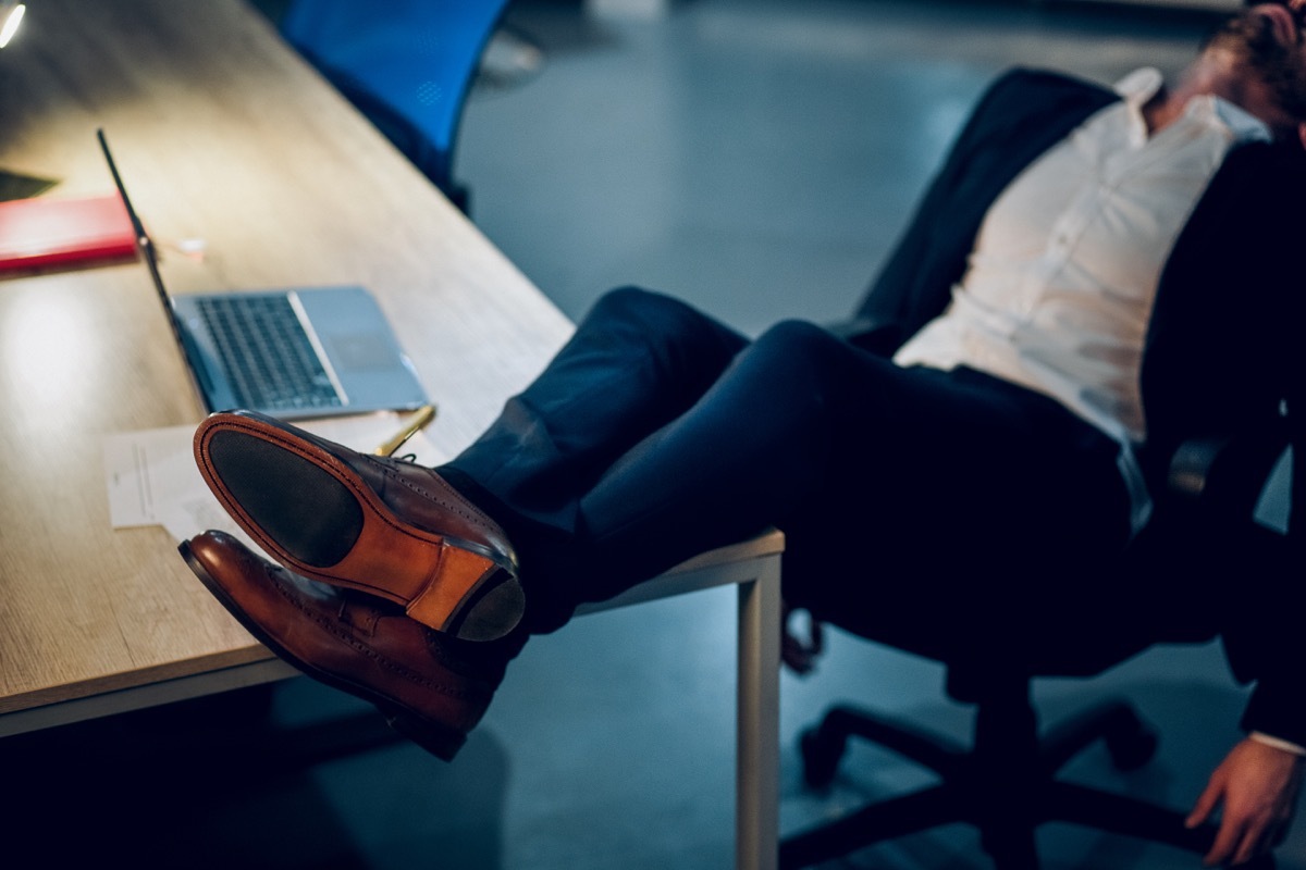 man kicking his feet up on a desk and sleeping in the office