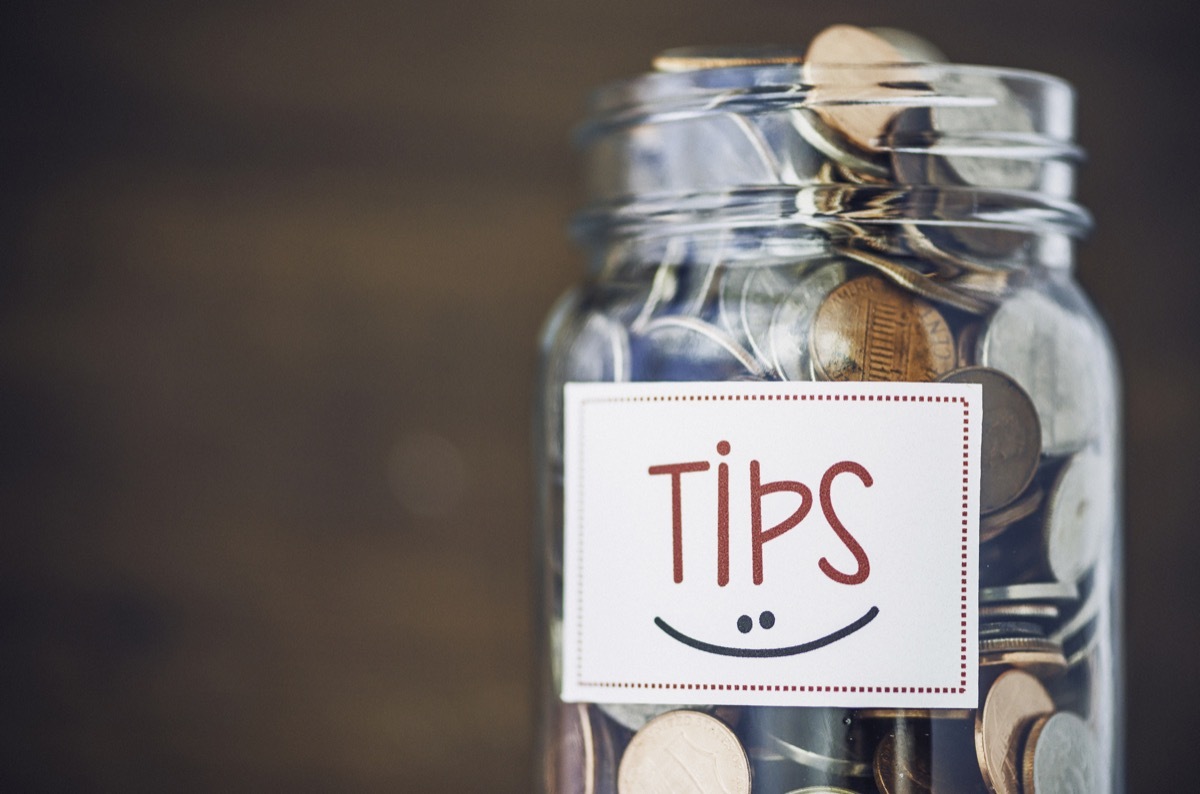 Tip jar with American currency on brown background