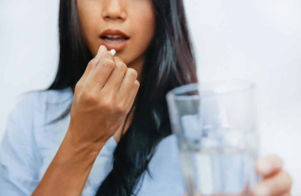 business woman taking a pill to ease her headache.