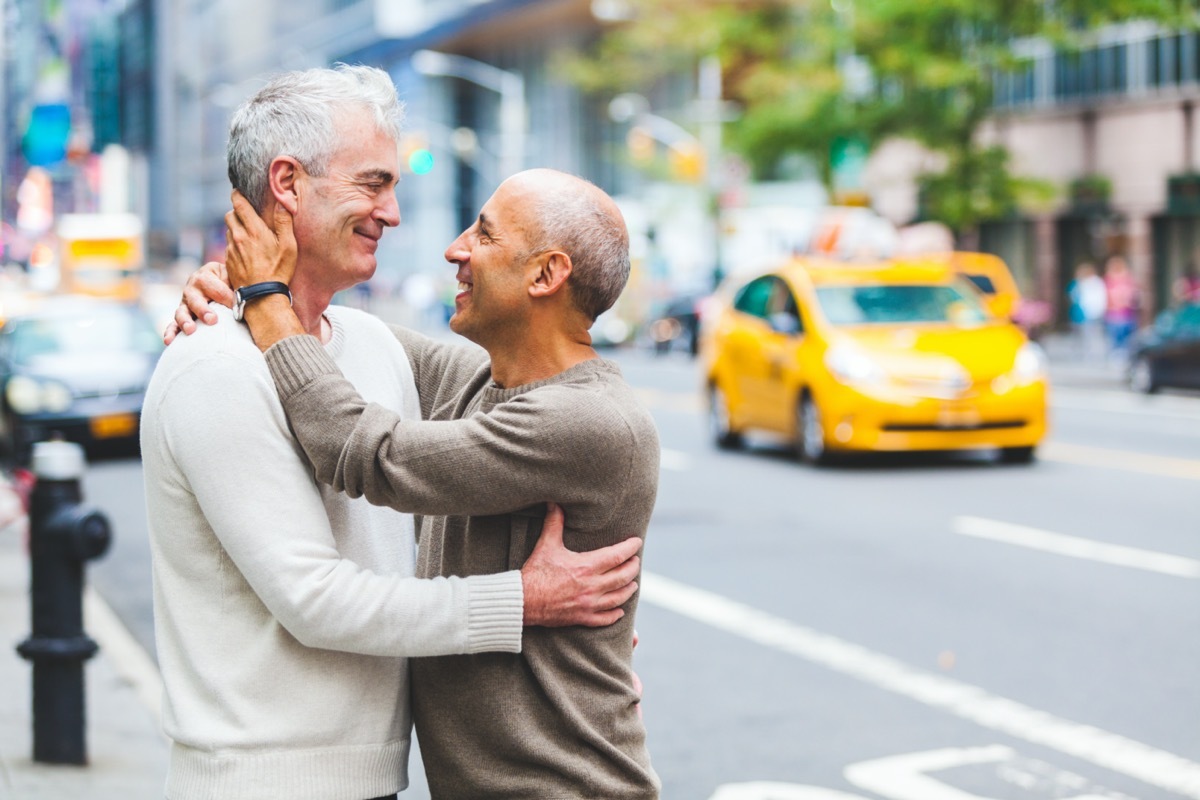 Two senior men hugging on city street