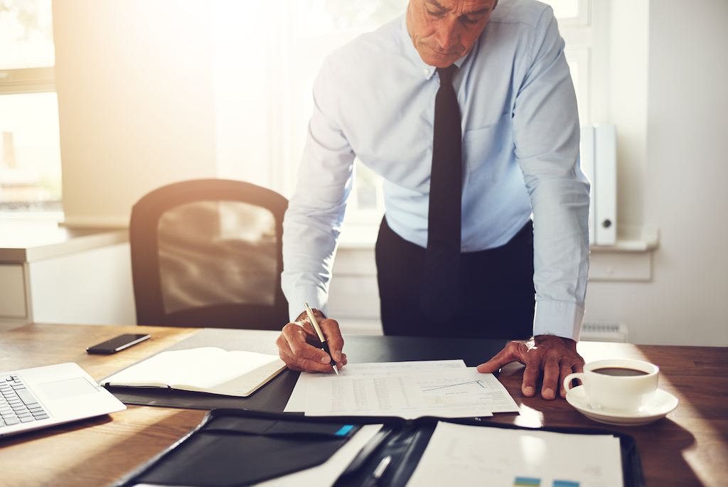 businessman with his hands on his desk in a position of power