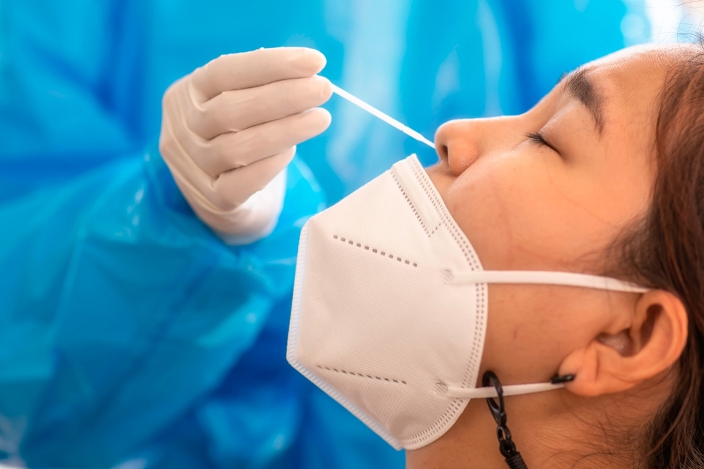 A woman getting a nasal swab from a healthcare worker as part of a COVID-19 test