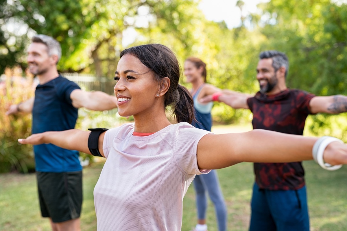 Woman exercising outside with a group of people.