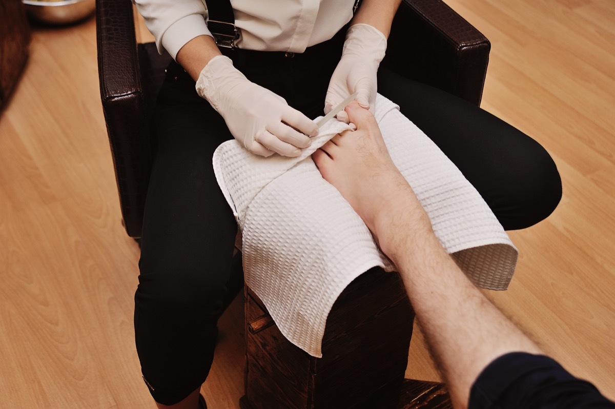 a young girl makes a man pedicure in the background of a beauty salon. Nail care