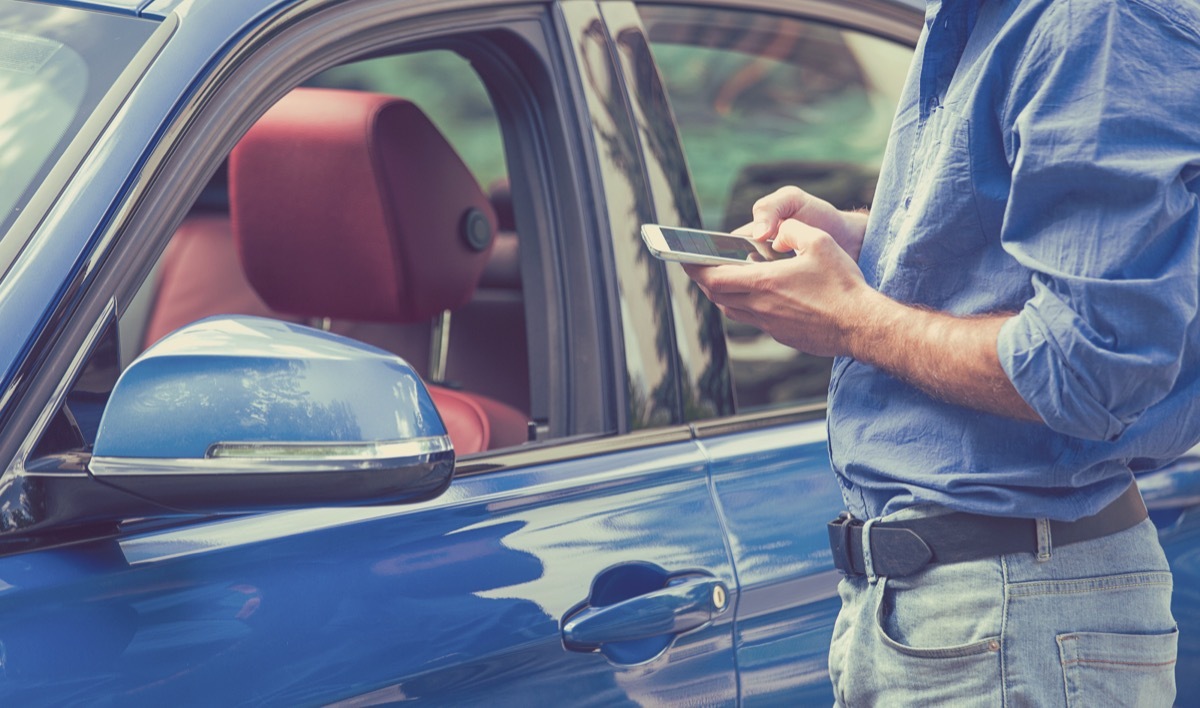 man looking at his phone for photos of his rental car