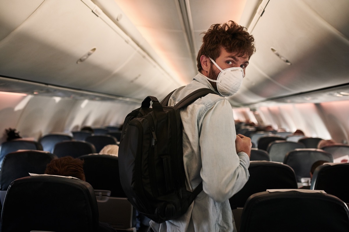 Shot of a young man wearing a mask and boarding an airplane