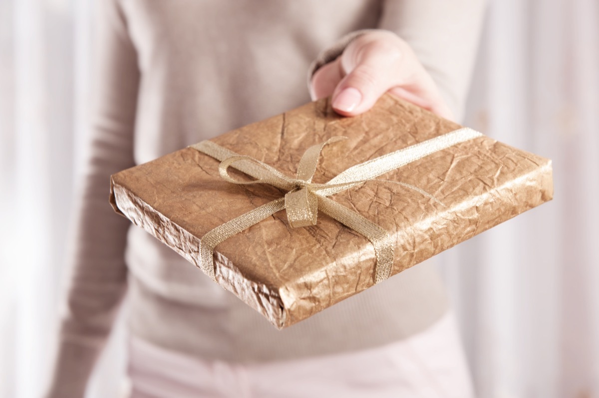 woman handing over gold wrapped book