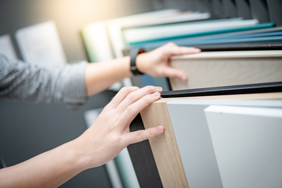 Male hand choosing cabinet panel materials or countertops for built-in furniture design.