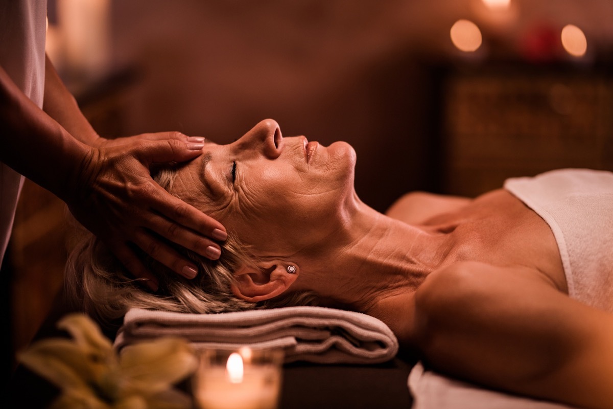 older white woman getting her head massaged at a spa