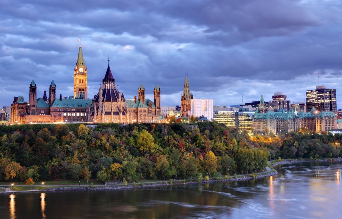 parliament Hill atop a dramatic hill overlooking the Ottawa River in Ottawa, Ontario in autumn. Parliament Hill is home to Canada's federal government and is the centrepiece of Ottawa‚Äôs downtown landscape. Ottawa is known for is high-tech business sector, vast array of museums and high standard of living.