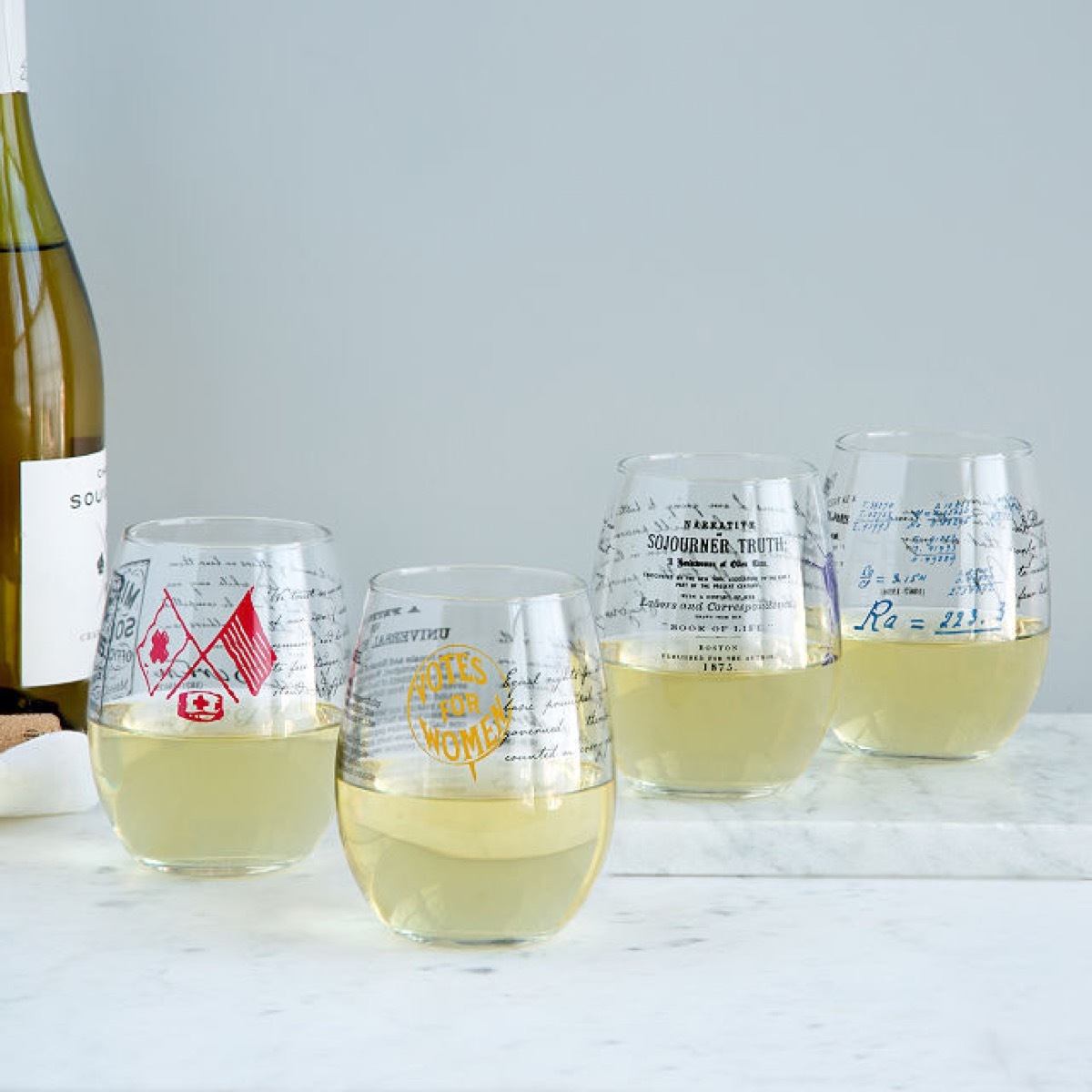 four stemless wine glasses with white wine in them