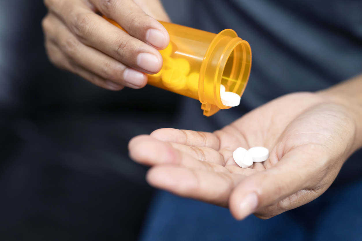 A close up of hands holding a prescription bottle and medication