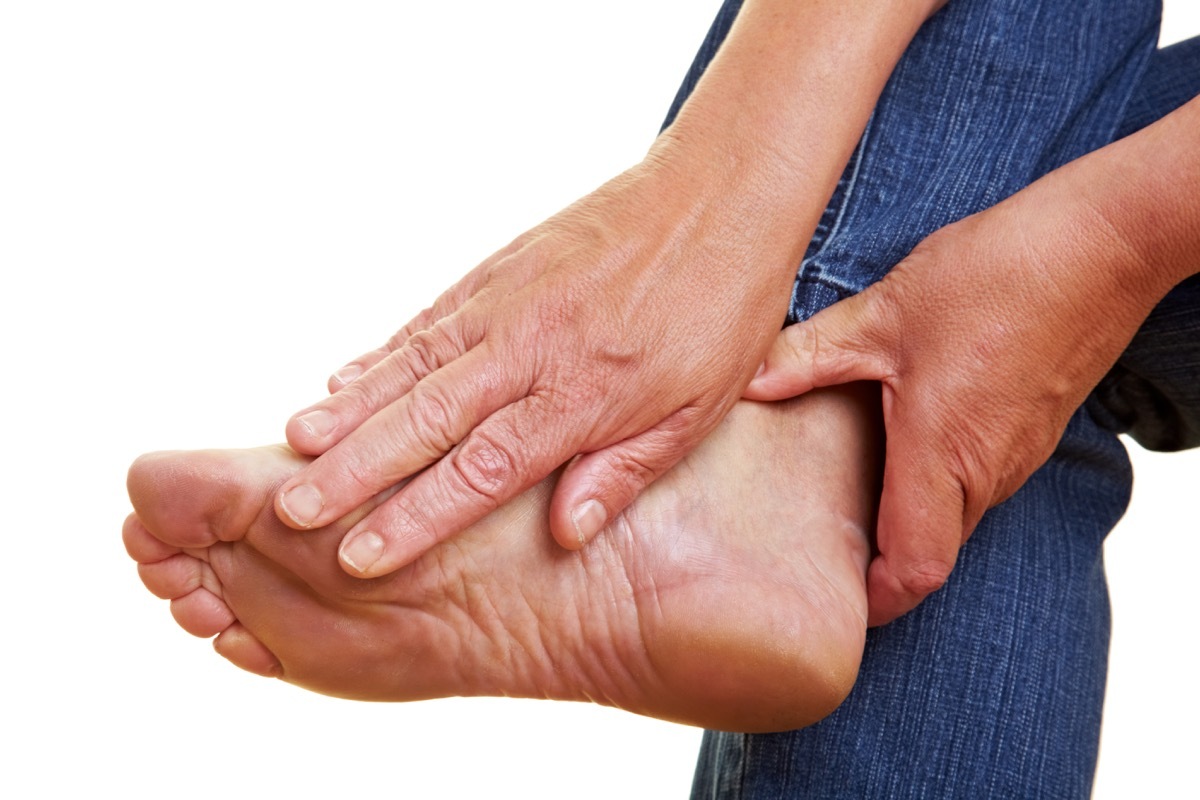 Woman Rubbing Her Foot in Pain Aching Feet