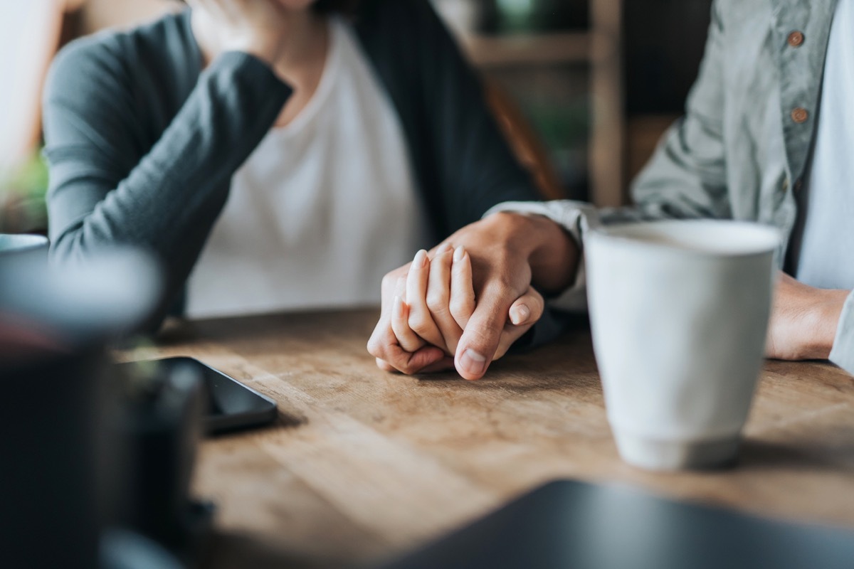 Close up of young couple on a date in cafe, holding hands on coffee table