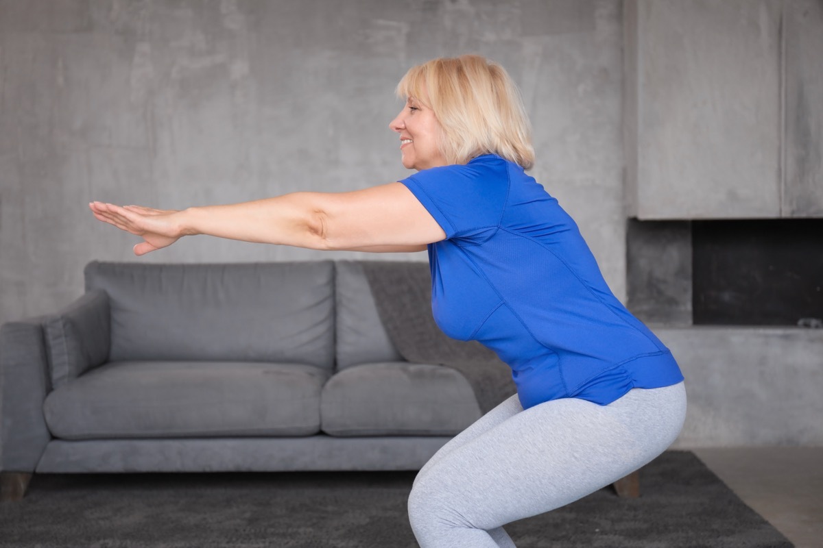 Older woman doing squats in the living room