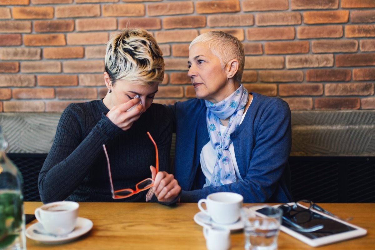 Sad and unhappy daughter sitting in cafe bar or restaurant with her mother and talking