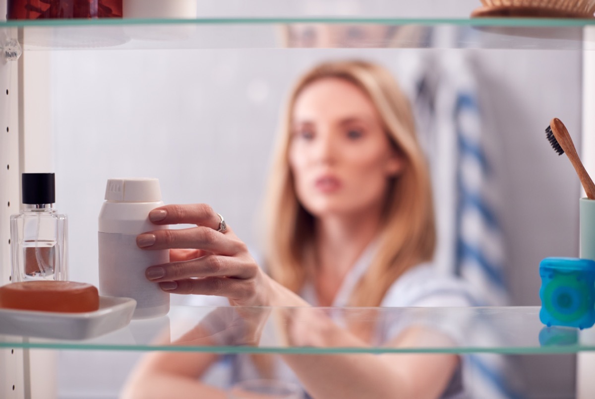 Woman opening medicine cabinet