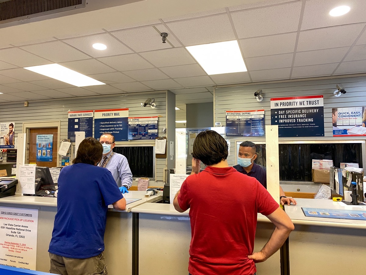 People mailing packages at a United States Post Office in Orlando, Florida where people are wearing face masks and social distancing,